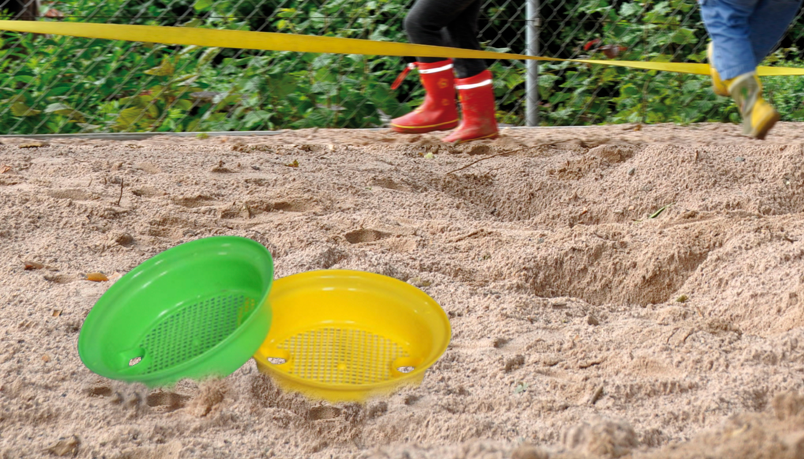 Sandsiebe Gelbes und grünes Sandsieb liegen im Sand