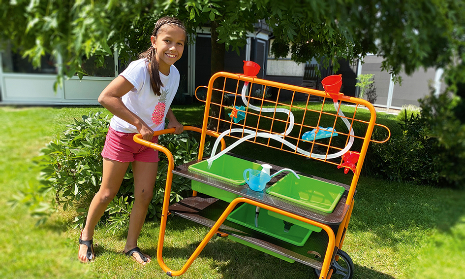 Mobiler Wassertisch I Wasserspieltisch I Dragon Toys Mädchen schiebt draußen mobilen Waschtisch