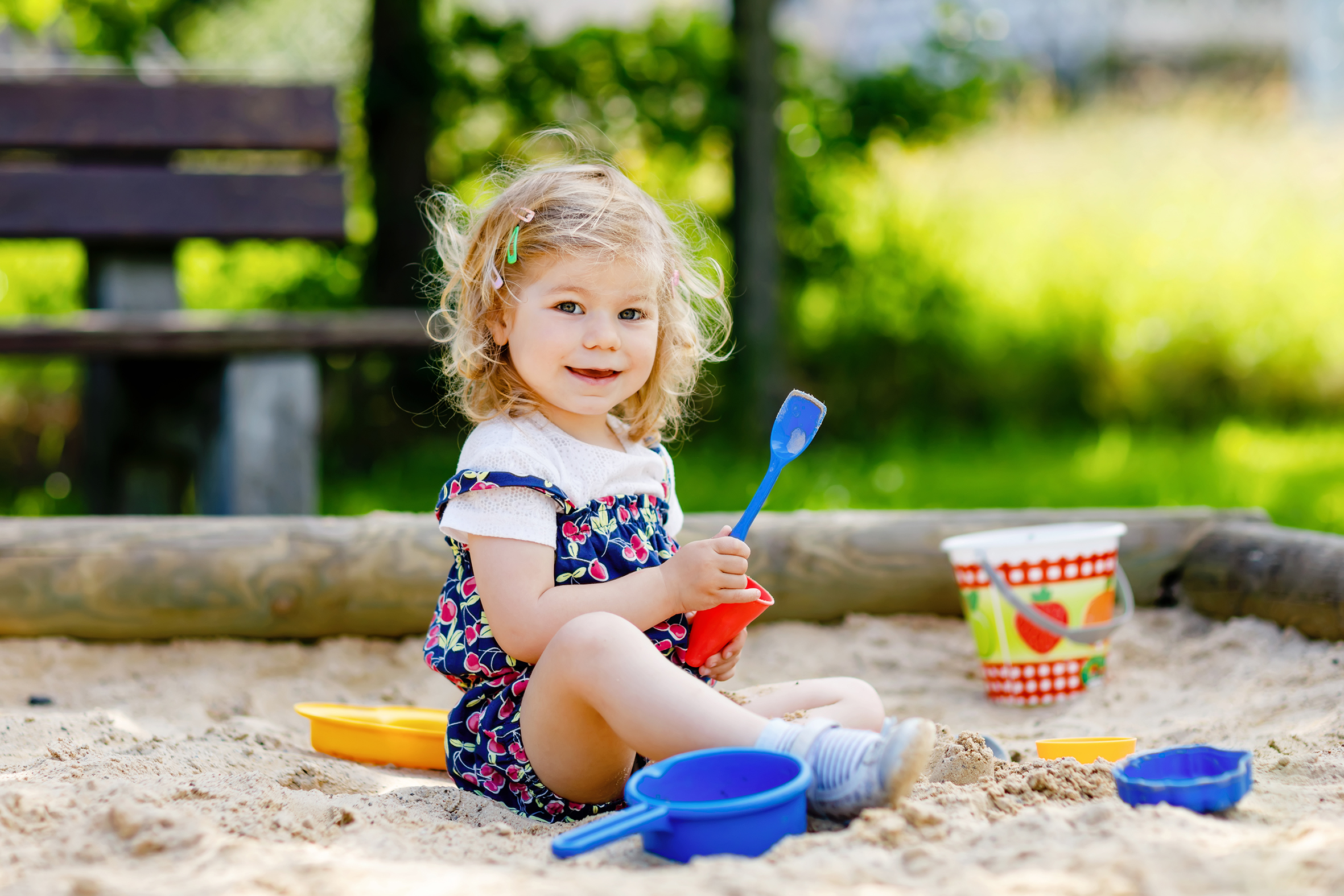 Mädchen sitzt spielend im Sandkasten