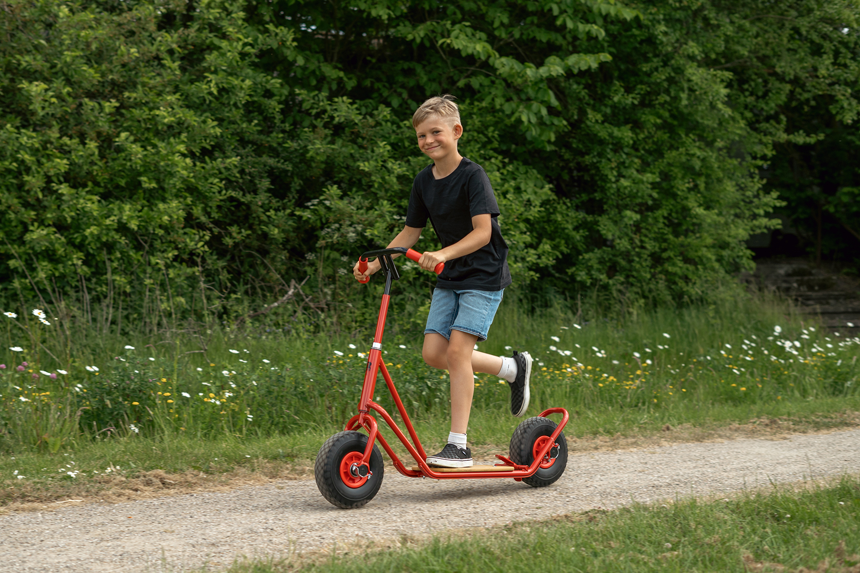 Großer Junge fährt stehend auf ROSE Roller