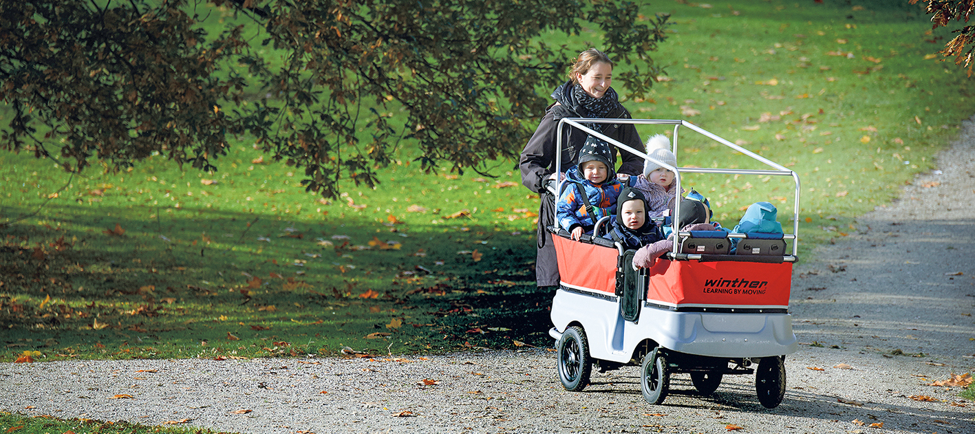 Tagesmutter schiebt Kinder im Krippenwagen von Winther Tagesmutter schiebt Kinder im Krippenwagen von Winther