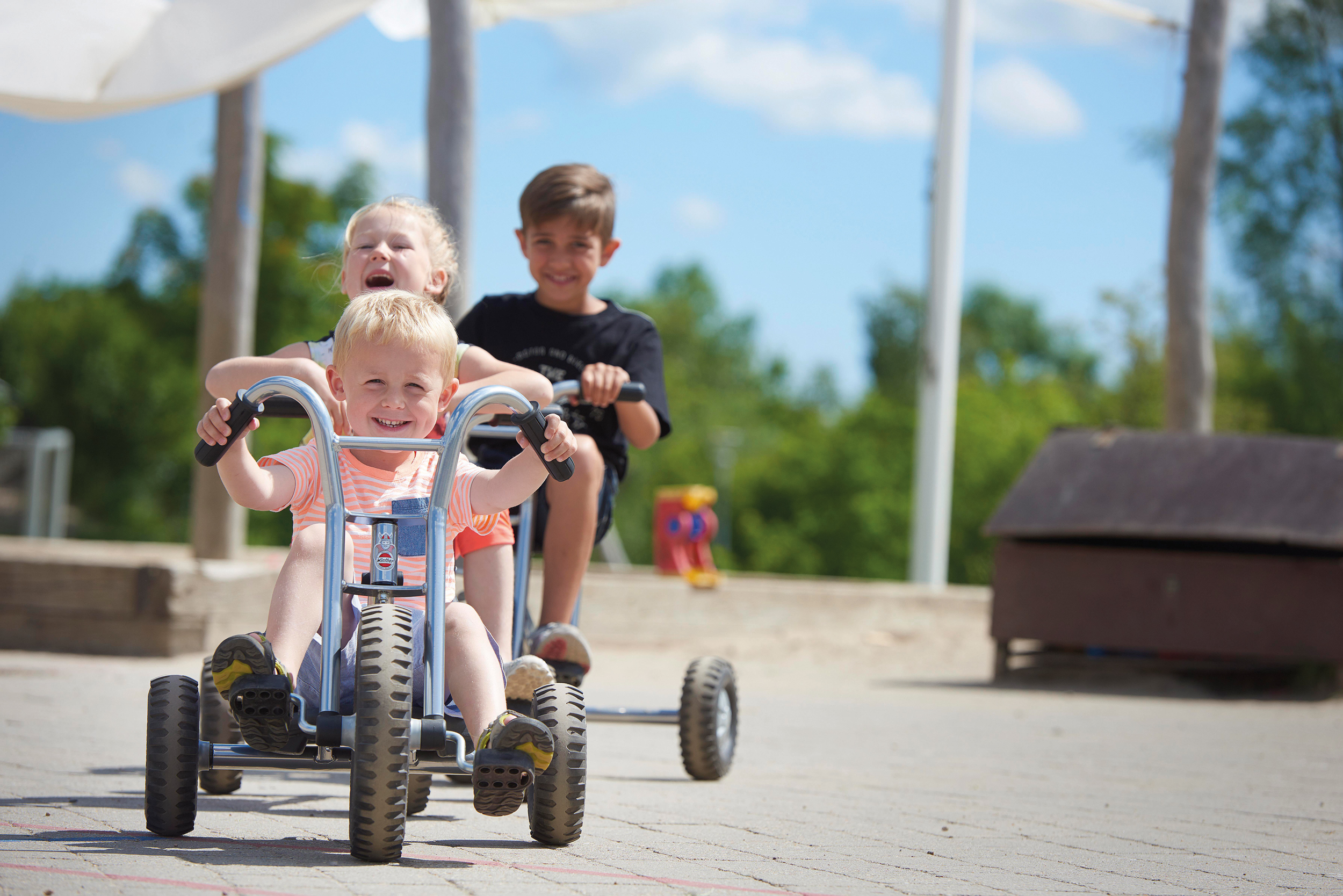 Kinder spielen draussen mit Winther Fahrzeugen