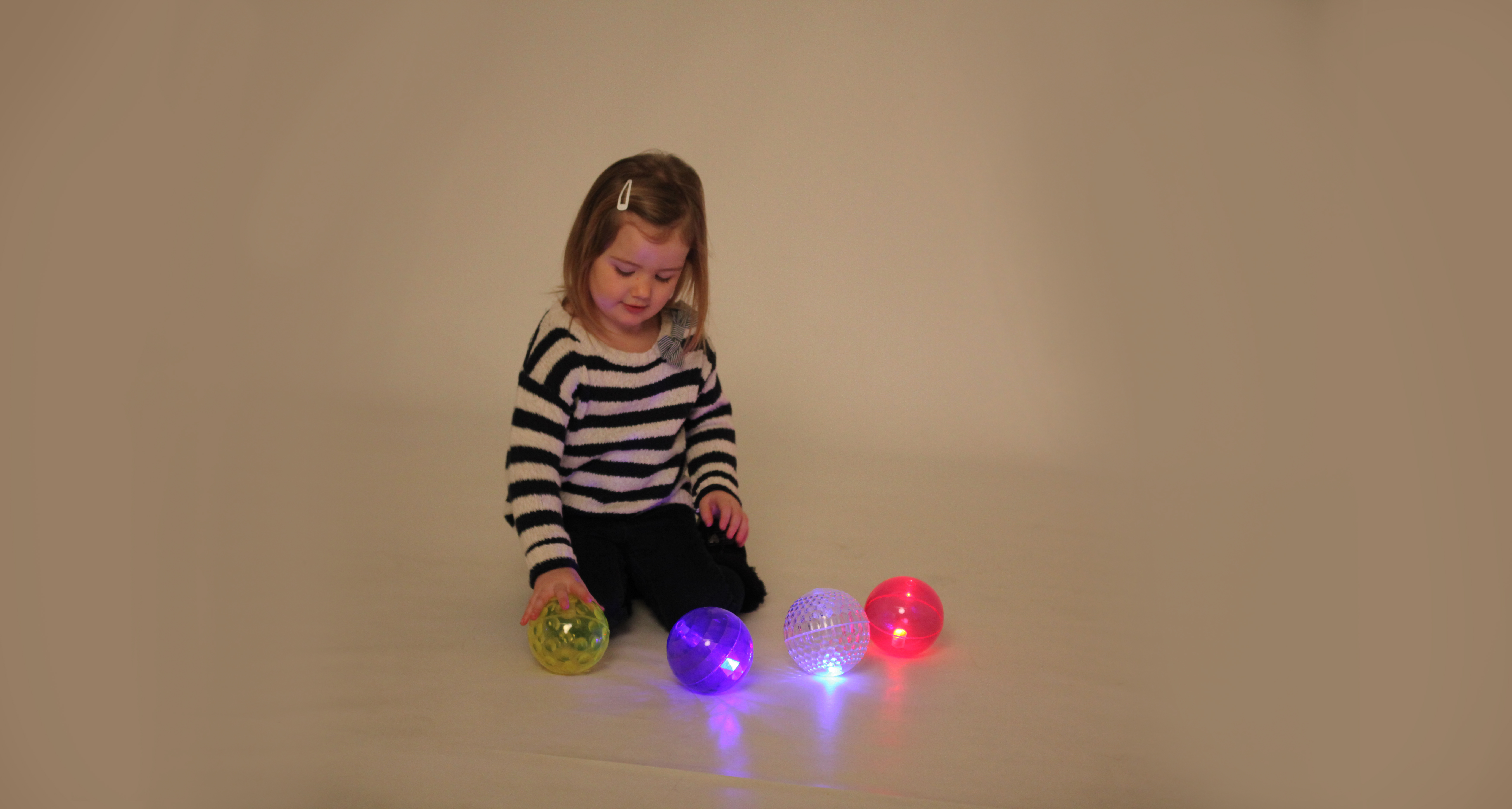 Mädchen auf dem Boden spielend mit Sensorikbällen Mädchen auf dem Boden spielend mit Sensorikbällen