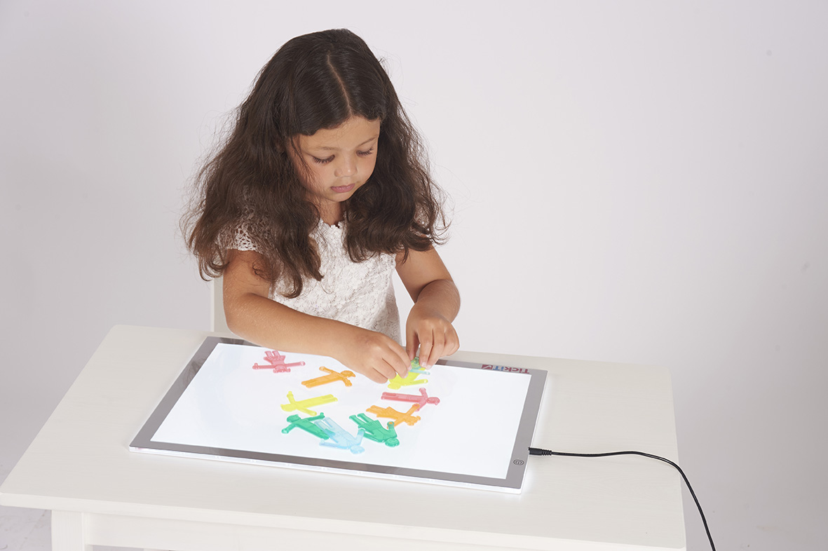 Leuchtplatte I Dragon Toys Mädchen legt Papierfiguren auf Leuchtplatte