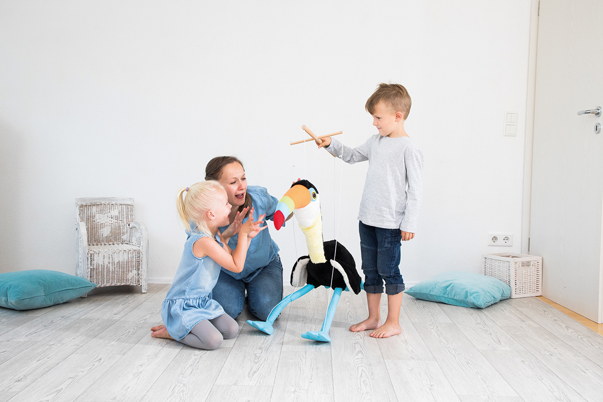 Handmarionette Tukan Toni I Sprachfoerderung Junge hält Tukan Handmarionette vor Erzieherin und kleines Mädchen